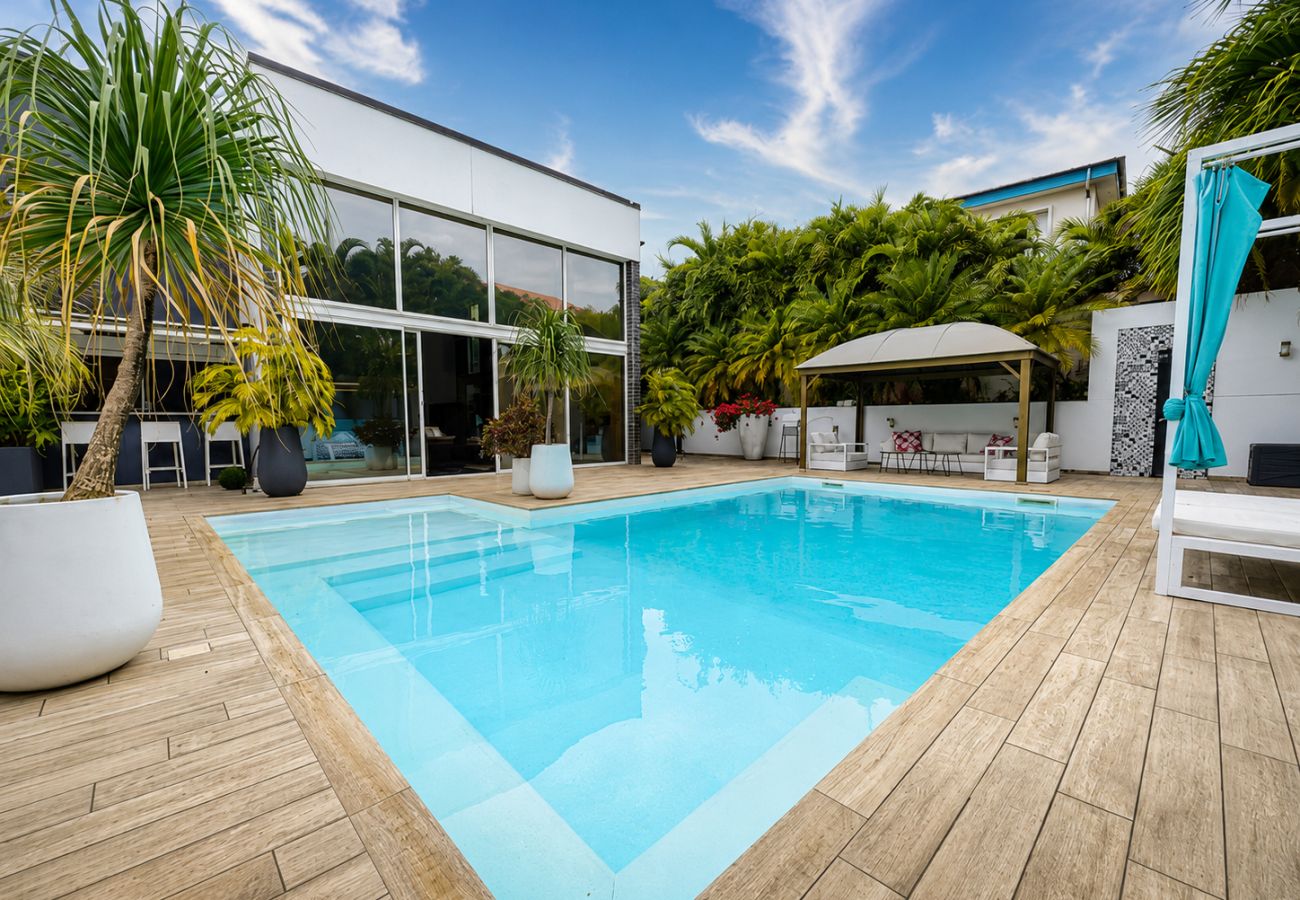 Piscine moderne avec terrasse en bois et jardin tropical